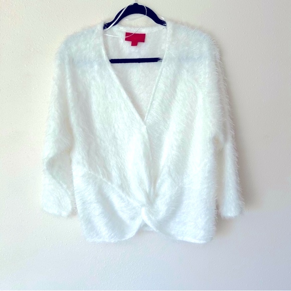 Jennifer Lopez white soft fluffy sweater has a knot detail in the front below V